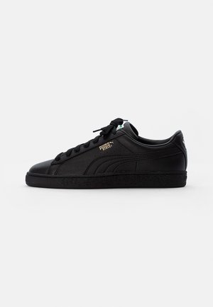 Baskets basses Puma Basket noires avec lacets noirs, semelle texturée et logo Puma doré sur le côté.