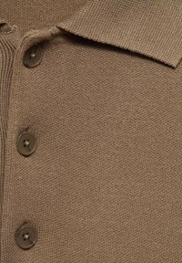 Close-up of brown knit cardigan with a pointed collar and three dark buttons down the front.