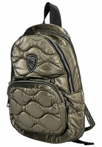 Sac à dos matelassé vert olive avec finition brillante, plusieurs poches zippées, un écusson de logo et un design texturé et rembourré.