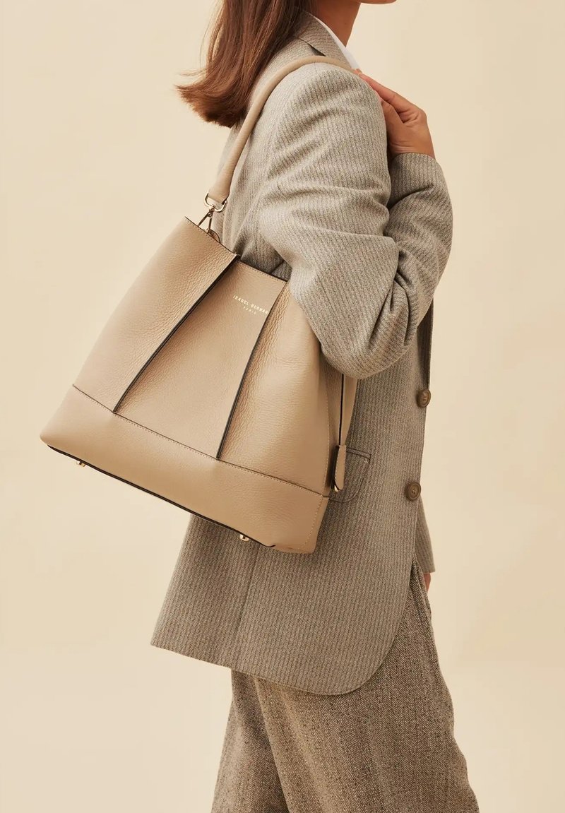Beige leren tote bag met een gestructureerd ontwerp, voorzien van twee handvatten aan de bovenkant en subtiele stiksels. Glad oppervlak en vlakke bodem.