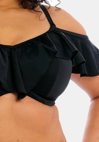 Top bikini nero con maniche a sbuffo e volant, dotato di spalline regolabili. Realizzato in tessuto elastico con una superficie liscia e un design aderente.