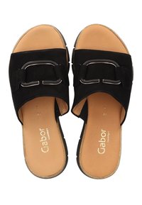 Czarne zamszowe klapki z szerokim paskiem ozdobionym metalową klamrą, brązową wkładką i teksturowaną podeszwą.