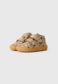 Beige Wildlederschuheknöchel mit metallischen Punktmustern, ausgestattet mit zwei verstellbaren Klettverschlüssen und einer strukturierten Gummisohle.