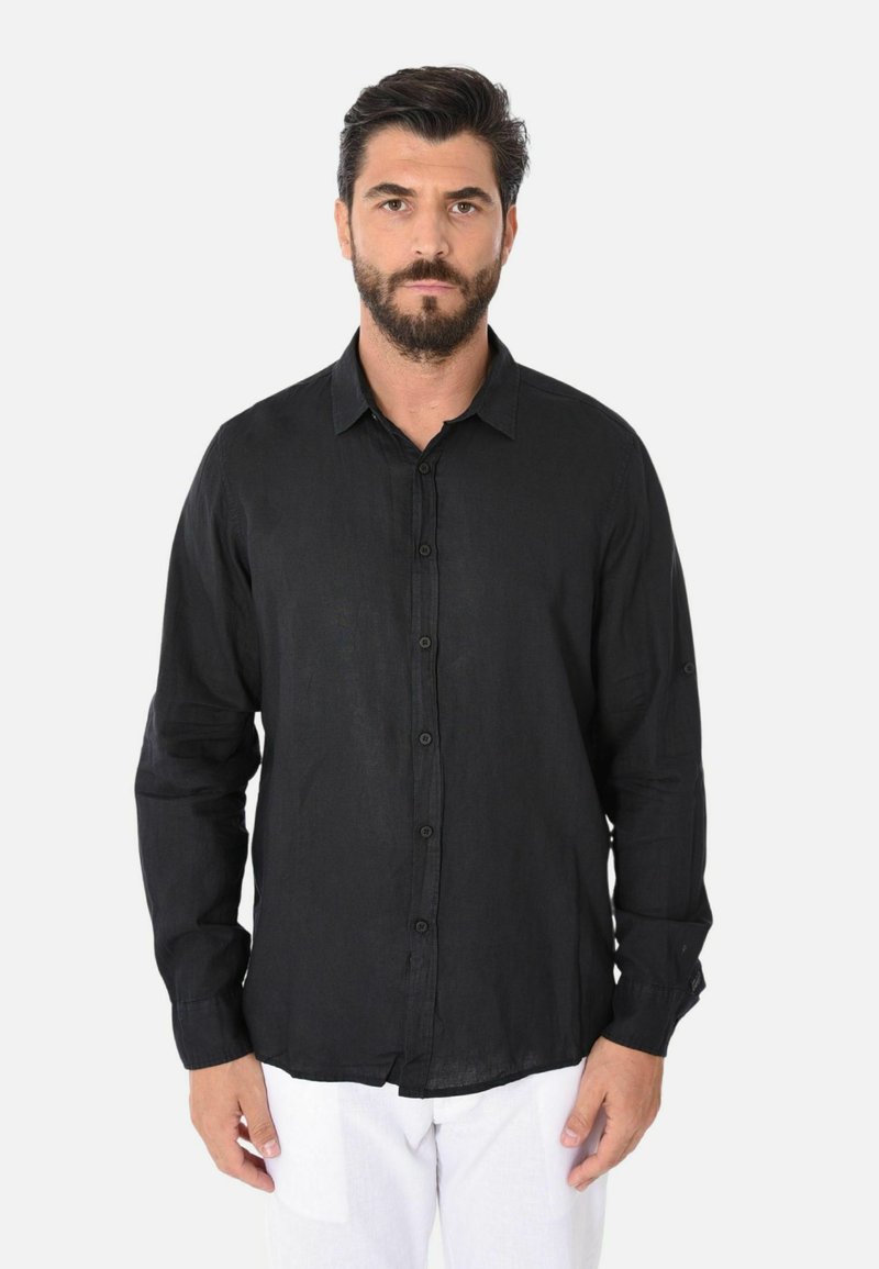 Camicia nera a maniche lunghe con bottoni realizzata in tessuto leggero, dotata di colletto classico e patta dei bottoni, indossata con pantaloni bianchi.