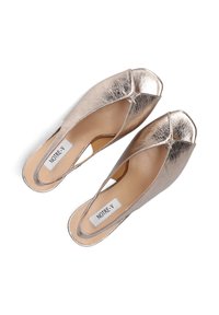 Metalen gouden slip-on schoenen met een peeptoe ontwerp, voorzien van een opvallende kruisband en een subtiel merklabel aan de binnenkant.