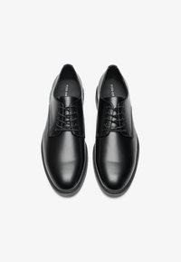 Black leather lace-up shoes with a smooth finish, rounded toe, and minimal design. Simple lacing system and flat rubber sole.