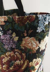 Blomster tote-väska med livliga rosor och syren på en mörk bakgrund, med kraftiga svarta handtag för enkel bärande.