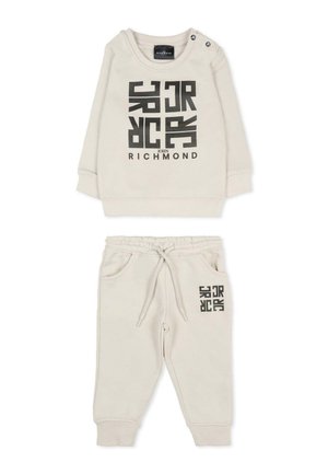 Tuta per bambino color beige chiaro con stampa grafica nera. Comprende una maglietta a maniche lunghe con bottoni sulle spalle e pantaloni con vita elastica e tasche.
