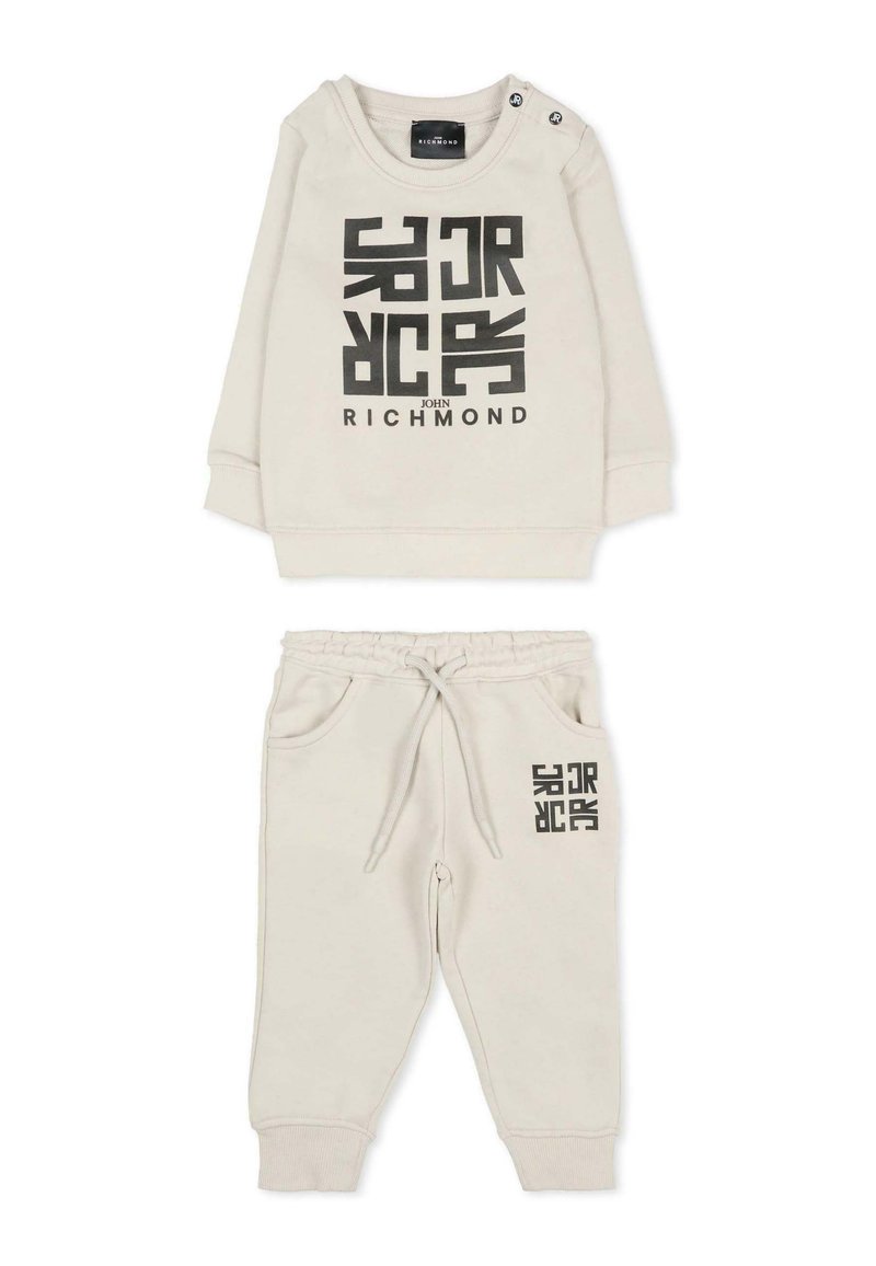 Jasny beżowy dres dla małego dziecka z czarnym nadrukiem graficznym. Zawiera bluzę z długim rękawem z zapięciem na ramionach oraz spodnie z elastycznym pasem i kieszeniami.