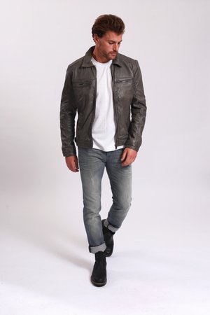 Graue Lederjacke mit Reißverschlusstaschen auf der Brust, über einem weißen Hemd getragen, kombiniert mit hellblauen, ausgewaschenen Jeans und schwarzen Stiefeletten.