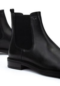Botas Chelsea de cuero negro con paneles elásticos laterales, puntera redondeada y tacón bajo. El diseño incluye detalles de costura.