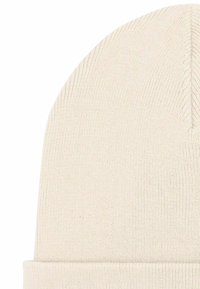 Crèmekleurige gebreide muts met opgerolde rand, met een gladde textuur en subtiele stikseldetails langs het midden.