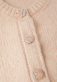 Tissu tricoté rose doux avec trois boutons ronds recouverts de tissu présentant un motif multicolore subtil en rangée verticale.