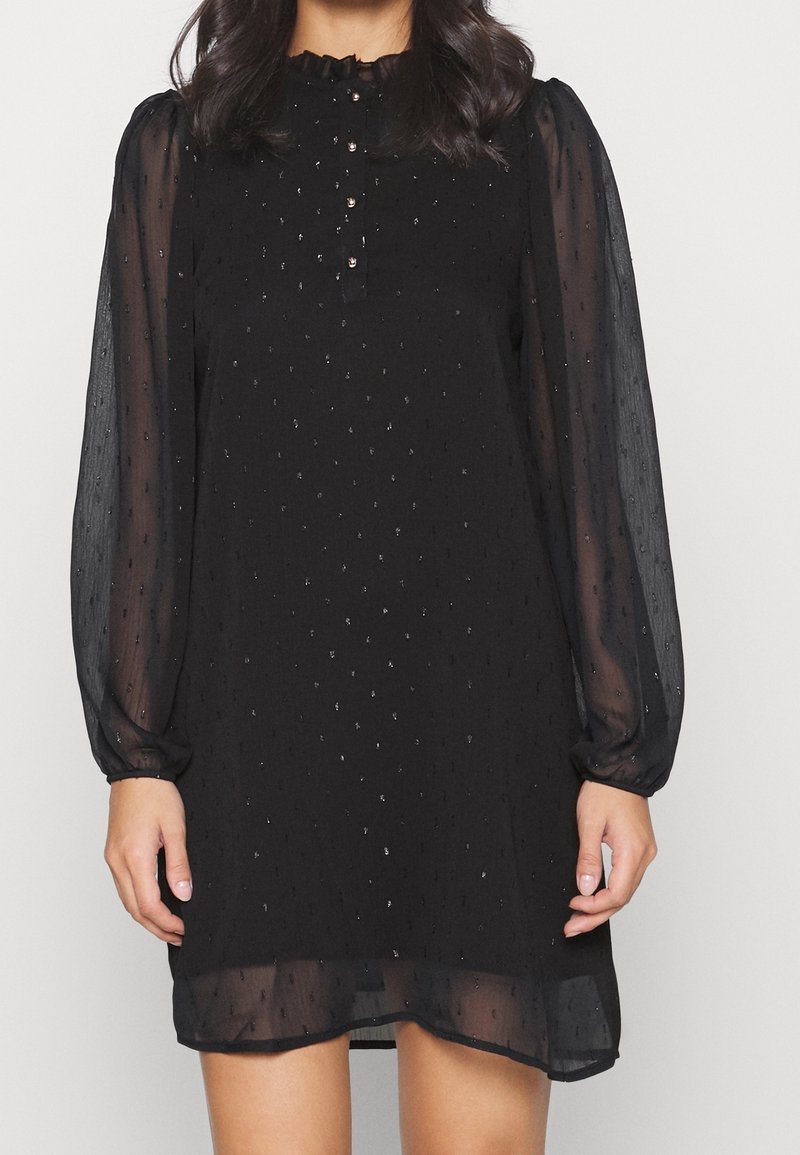 Black dress made of sheer fabric with puffed sleeves, ruffled neckline, and small decorative buttons. Has a textured pattern and a flowing silhouette.