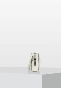 Bílá kožená taška přes rameno s texturovaným povrchem, na zip a s odnímatelným popruhem. Má obdélníkový tvar s kontrastním prošíváním.