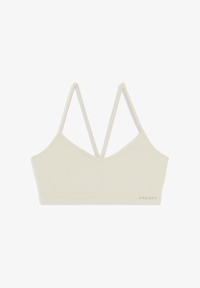 Bralette beige cropped avec texture côtelée, bretelles doubles ajustables et décolleté en V. Présente un logo brodé en bas.