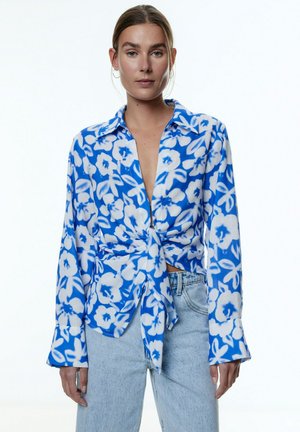 Blouse met bloemenpatroon in blauw, met lange mouwen, kraag en geknoopte voorkant. Lichtgewicht stof, soepele textuur en een relaxte pasvorm.