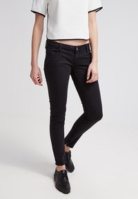 Jeans ajustados negros en una mezcla de algodón, con cierre de botón en la parte delantera, bolsillos delante y detrás, y detalles con cremallera en el tobillo.