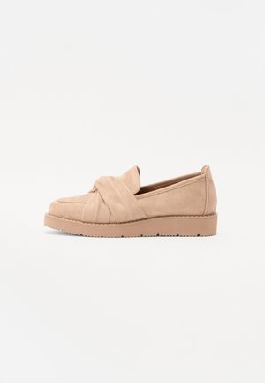 Beige nubukist libist jalatsid, mille pealsel on sõlme detail, lamedate tallade ja tekstureeritud kummist välispinnaga, mis tagab haarde.