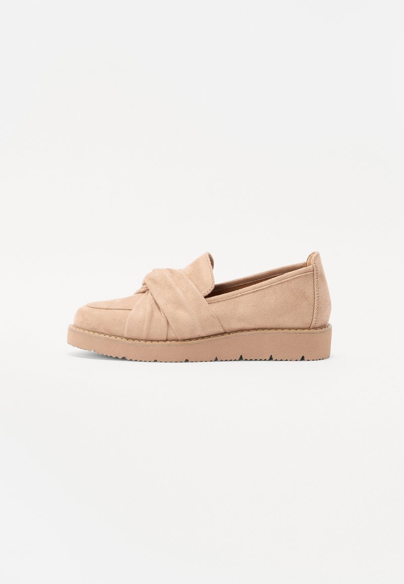 Pantofi slip-on din suede bej, cu un detaliu legat în partea superioară, având o talpă plată și o talpă exterioară din cauciuc texturat pentru aderență.