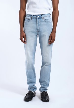Licht gewassen denim jeans met een slim fit, voorzien van vijf zakken, een knoopsluiting en subtiele vervaging. Gedragen met zwarte instappers.