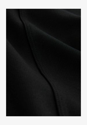 Närbild av svart tyg med fin räfflad struktur och synlig söm som löper diagonalt över ytan.