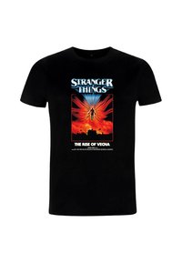 Camiseta negra con el texto "Stranger Things" sobre un fondo ardiente en tonos rojos y naranjas que muestra una figura flotante y una casa en silueta debajo.