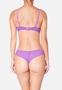 Ensemble de lingerie violet fabriqué en tissu doux, avec des bretelles réglables, une fermeture à crochets au dos et un bas avec une couverture minimale.