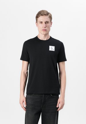 Black short-sleeve t-shirt made of cotton with a crew neckline and a small white square logo featuring "cK" on the left chest area.