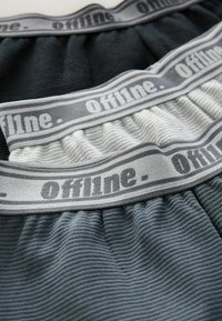 Lyocell-sekoitusshortsit, joissa on ribbitekstuuri, musta ja harmaa väri, sekä pehmeä joustava vyötärö, jossa on harmaalla painettu "Offline.".