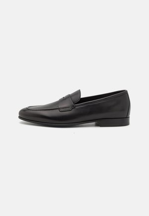 Black leather men's loafer with a low heel and a classic penny strap design, shown in side profile on a white background.