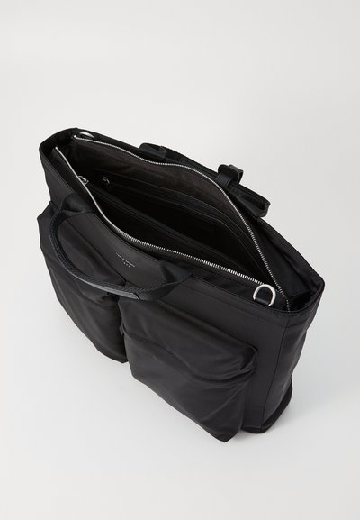 Sort tote bag lavet af nylon med to udvendige lommer, lynlåslukning i toppen og dobbelte håndtag. Indvendigt har den flere rum.