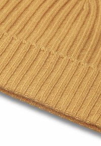 Berretto a coste di colore giallo senape con una texture morbida e un orlo piegato, che presenta linee verticali uniformi e una costruzione senza cuciture.