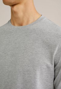 Camiseta de algodón gris de cuello redondo con una textura suave y mangas cortas, que muestra un diseño clásico y sencillo.