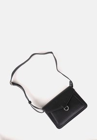Borsa a tracolla in pelle nera con chiusura a pattina, un accento a cerchio in argento e tracolla regolabile. Texture liscia e forma rettangolare.