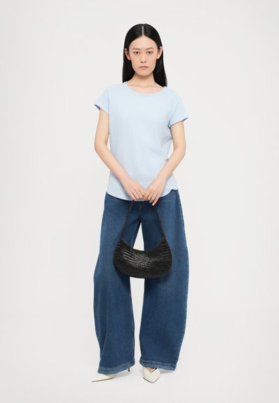 Light blue short-sleeve t-shirt paired with loose dark blue denim trousers and a woven black handbag. Slim, pointed white heels complete the look.