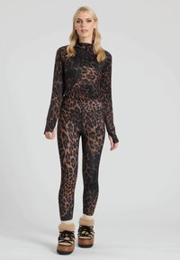 Set da allenamento con stampa leopardata in tonalità nere e marroni, composto da un top con zip e leggings aderenti. Tessuto testurizzato, maniche lunghe e aperture per il pollice.