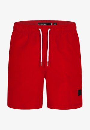 Punaiset uimapuvut, jotka on valmistettu kevyestä kankaasta. Niissä on joustava vyötärö, jossa on nyöri, sekä pieni musta logopatches sivussa.