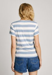 T-shirt rayé en coton bleu clair et blanc avec des manches courtes, un col rond et une coupe ajustée, associé à un short en denim.