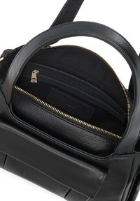 Sac à main en cuir noir avec fermeture éclair dorée partiellement ouverte, montrant une poche intérieure zippée et une boucle de poignée.