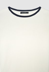 White knit top with a navy ribbed neckline. Tag reads "CALLIOPE" and size "S." Smooth texture, simple design, and no additional patterns.