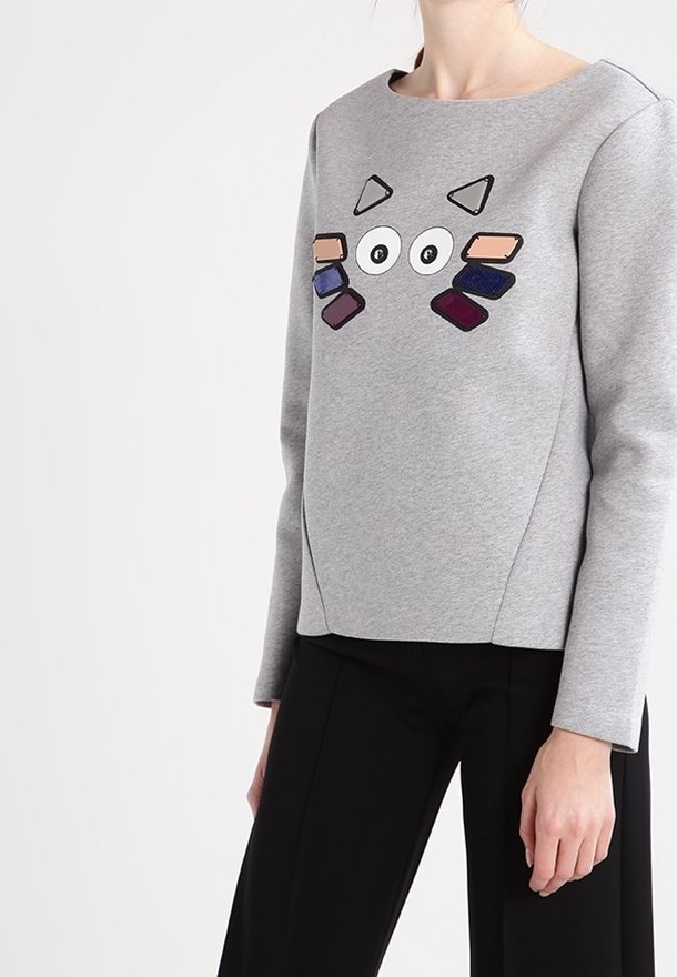 Sudadera gris con escote redondo y mangas largas, que presenta un diseño gráfico colorido y juguetón en la parte delantera con varias formas.