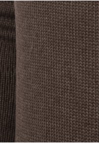 Ruskea neulottu kangas, jossa on tekstuuri, esittelee yhtenäistä kuviota ja pehmeää, untuvamaista pinta-alaa kauttaaltaan.