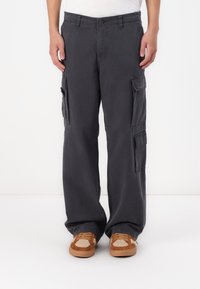 Grå cargo-bukser lavet af bomuld, med sidelommer, en afslappet pasform og en knaplukning, blevet parret med brune og beige sneakers.