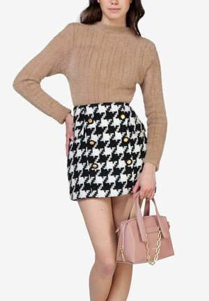 Maglione beige morbido, mini gonna houndstooth bianco e nero con bottoni dorati, e una borsa rosa con un accento a catena.