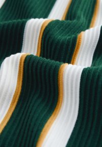 Gerippter Baumwollstoff mit abwechselnden horizontalen Streifen in Dunkelgrün, Weiß und Senfgelb, der Textur- und Musterdetails hervorhebt.