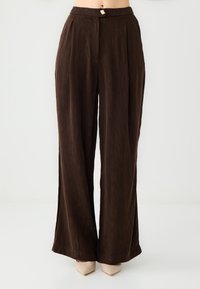 Braune, weit geschnittene Hosen aus strukturiertem Stoff, mit einem Bund und einem goldfarbenen Knopf sowie Frontfalten.