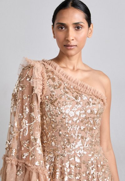 Beige one-shoulder kjole med palietter, kjoler med flæser langs halsudskæringen og gennemsigtig tekstureret stof på den ene ærme.