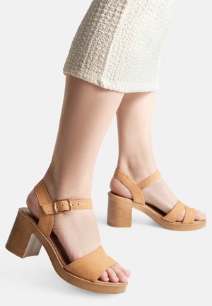 Hnedé kožené sandále na vysokom opätku s remienkom okolo členka, s tromi širokými pásmi cez prednú časť nohy a textúrovaným blokovým opätkom.