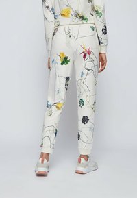 Vita joggerbyxor med färgglada blommönster och tunna linjeteckningar. Mudd vid anklarna och elastisk midja. I hopplock med lätta sneakers.